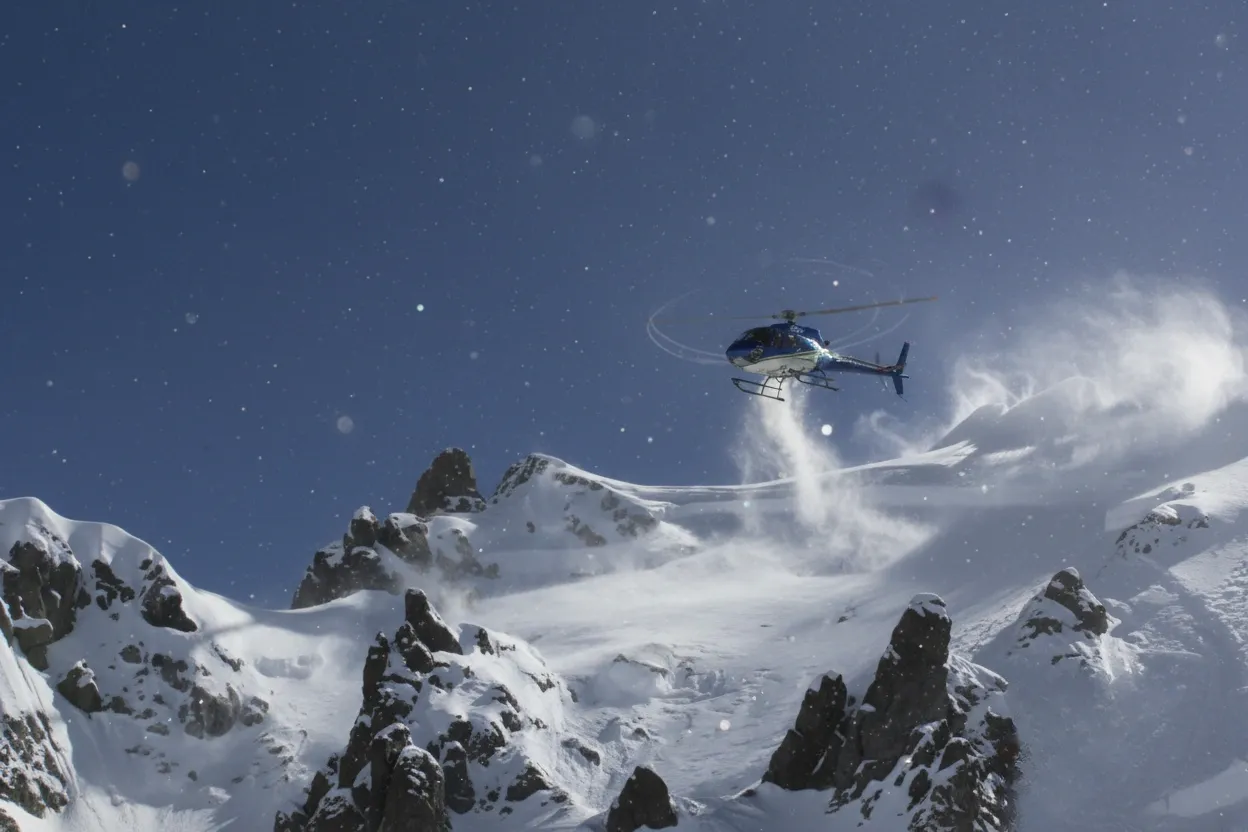 Skiers celebrating successful heli-skiing run with mountain backdrop